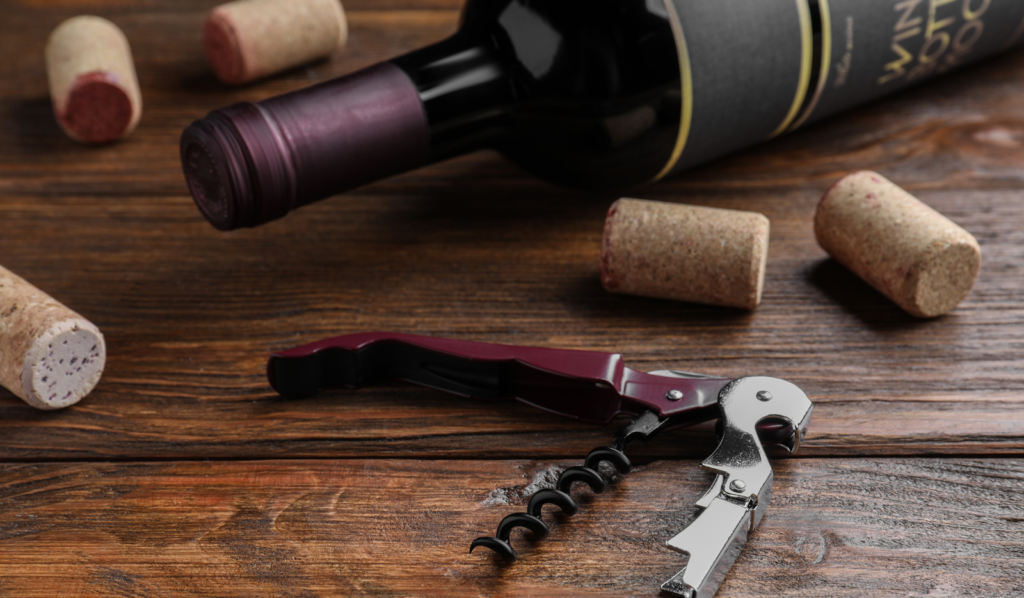 Wine bottle with corks and a waiter’s corkscrew on a wooden table