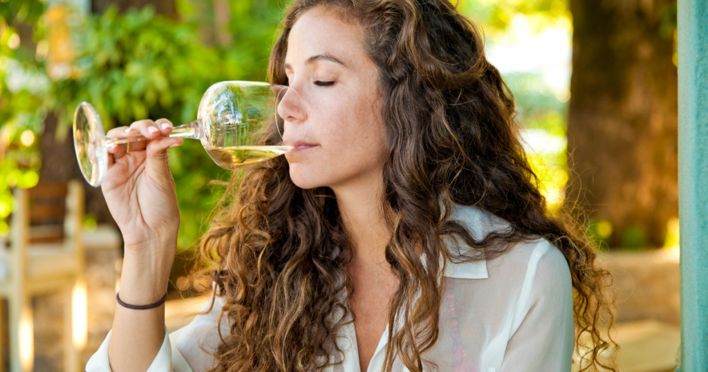 Woman drinking white wine outdoors in a garden setting