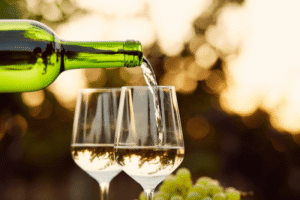Dry white wine being poured into glasses with grapes in the background