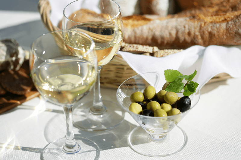 Dry white wine served with olives and bread on a table setting