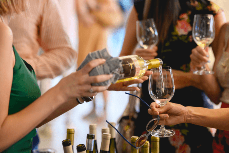 Pouring dry white wine into a glass at a social gathering