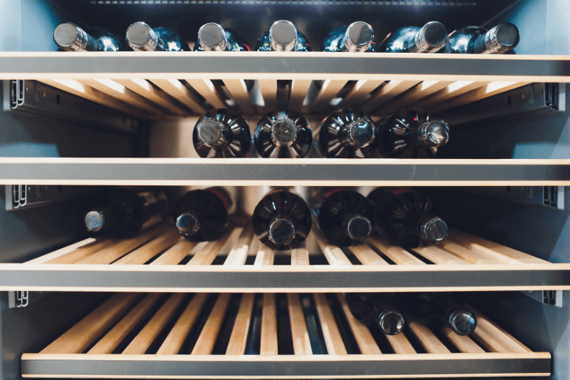 Close-up of wine bottles stored horizontally on wooden wine cooler shelves