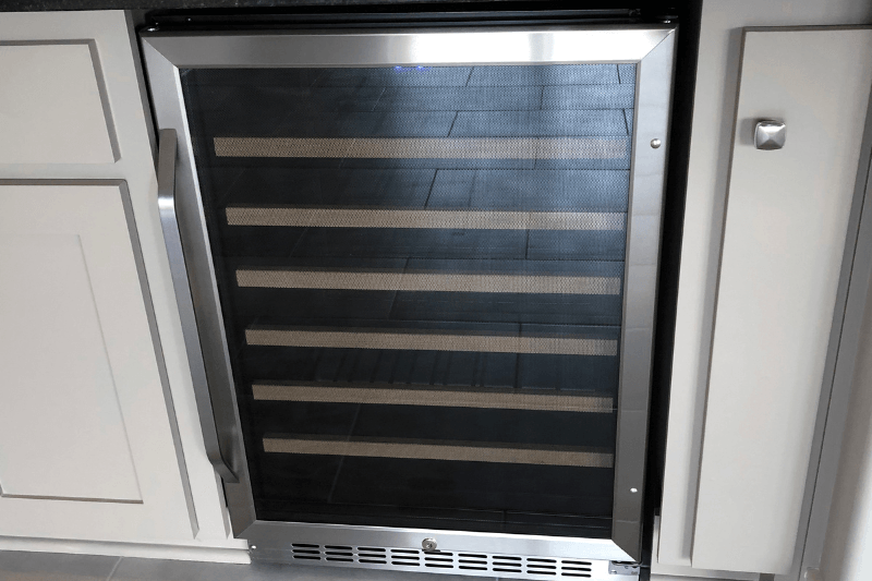 Empty under-counter wine cooler with glass door and front ventilation