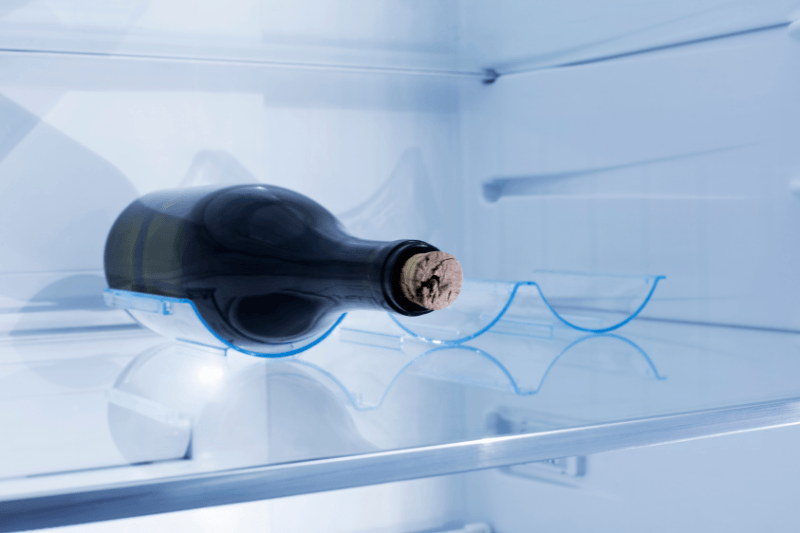 Unopened wine bottle stored horizontally in a refrigerator