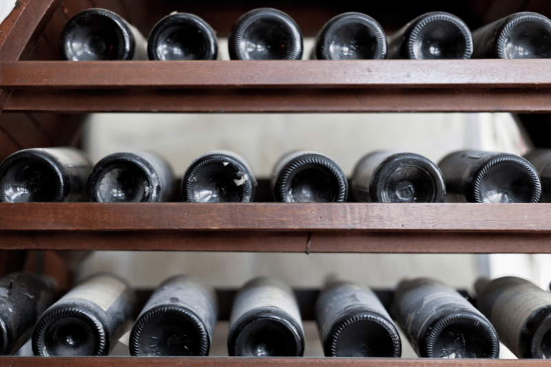 Unopened wine bottles stored horizontally on a wooden wine rack